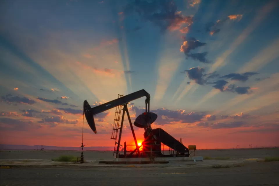 Oil well pump jack sillhouetted against a colorful sunset sky in California's San Joaquin Valley